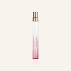 Perfume bottle with pink gradient and gold cap on a light beige background