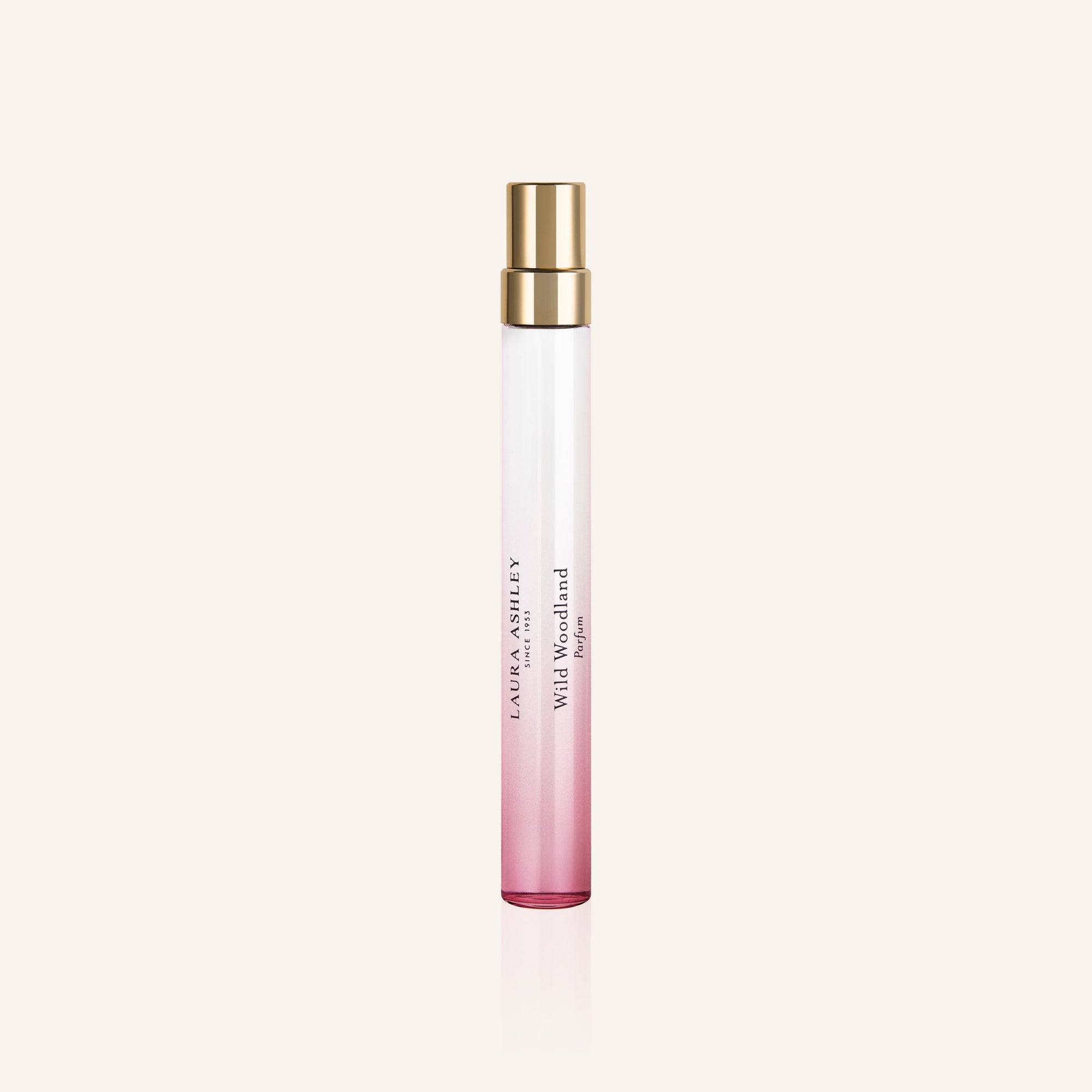 Perfume bottle with pink gradient and gold cap on a light beige background