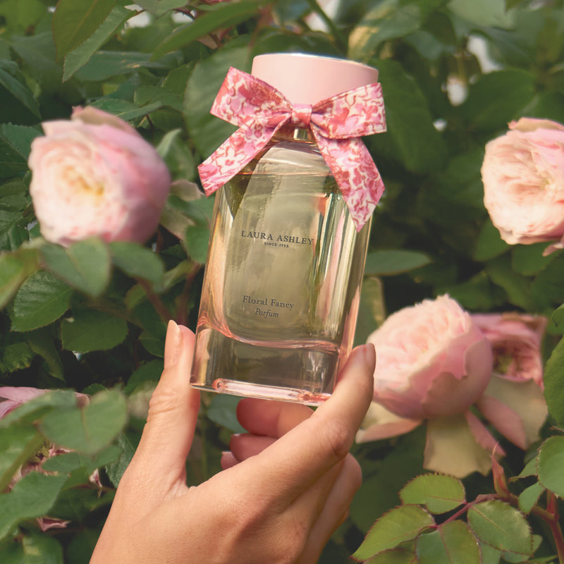 Laura Ashley Floral Fancy parfum bottle being held against rose garden
