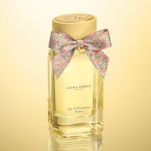 Laura Ashley Joy of Primrose perfume bottle with a floral bow on a yellow background