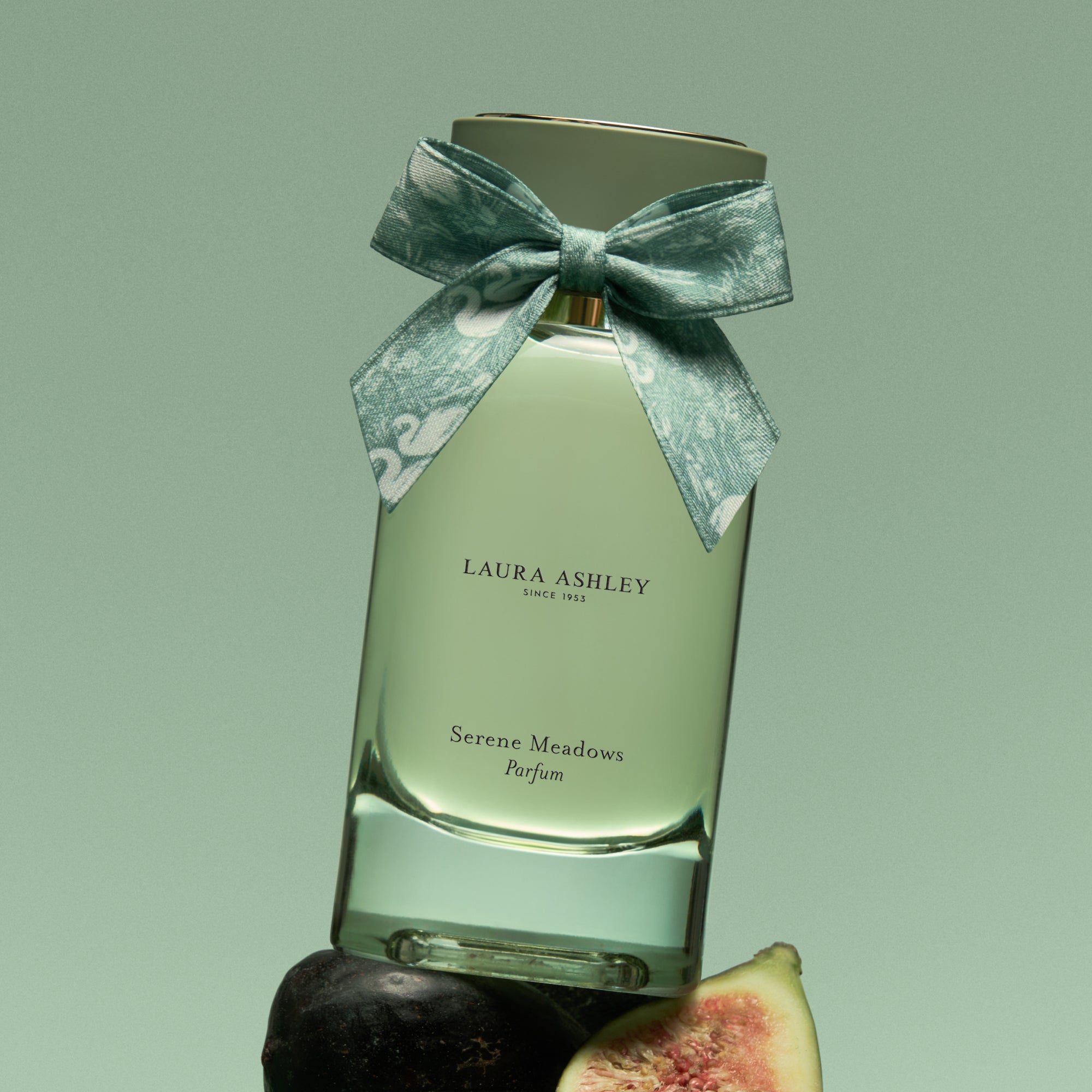 Laura Ashley Serene Meadows perfume bottle with a bow on a green background