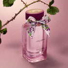 Laura Ashley Wild Woodland perfume bottle with a decorative bow and branding on a pink background.