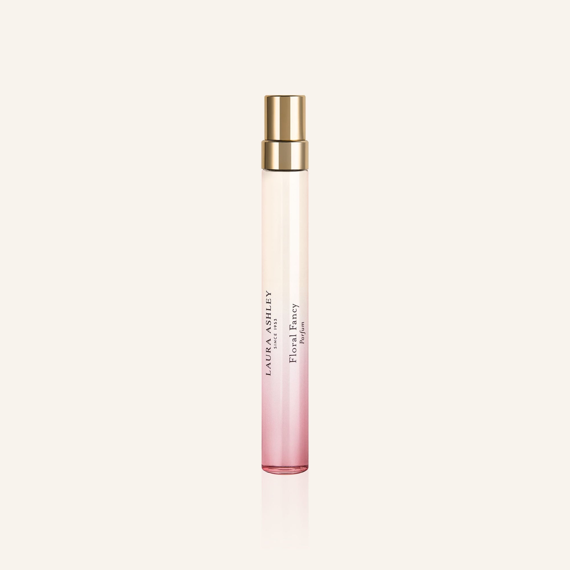 Laura Ashley Floral Fancy Perfume bottle with pink gradient and gold cap on a light beige background